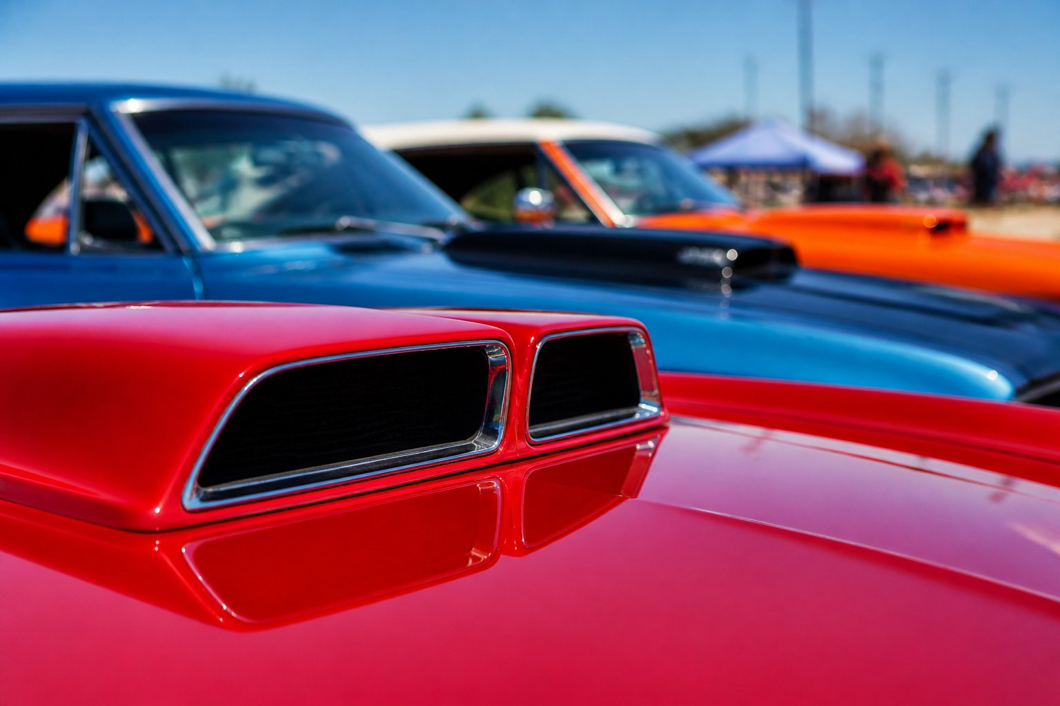 Close-up view of distinctive hood scoops and ram-air systems on several classic 1960s muscle cars parked outdoors.