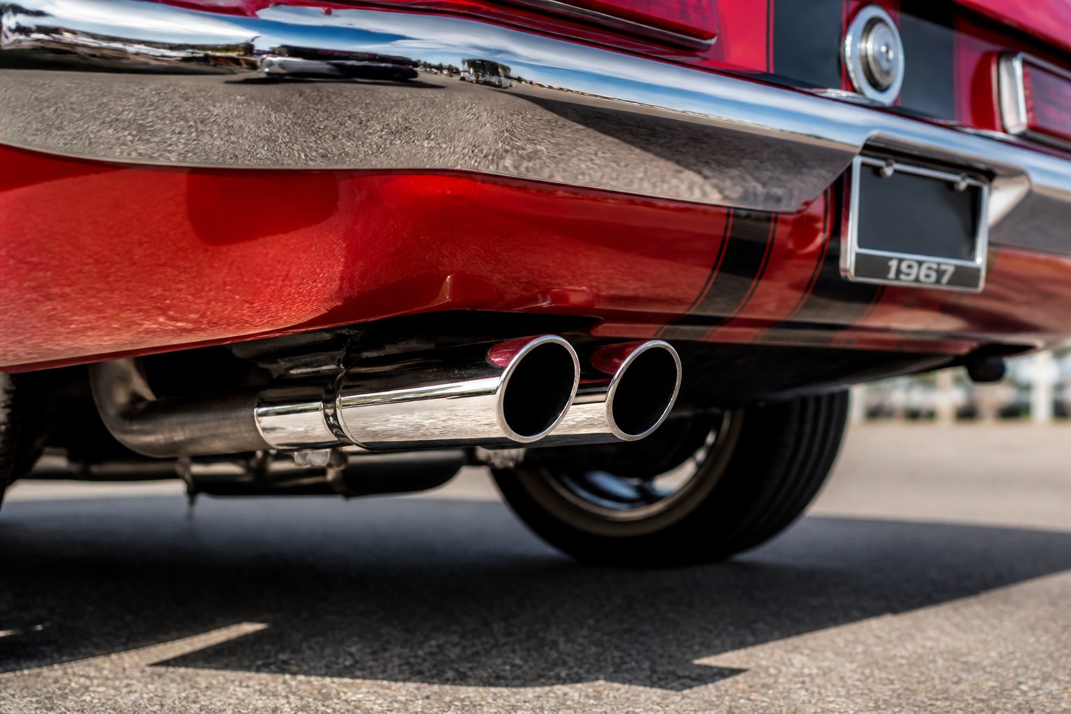 Close-up of dual chrome exhaust tips on the rear of a classic 1960s muscle car.