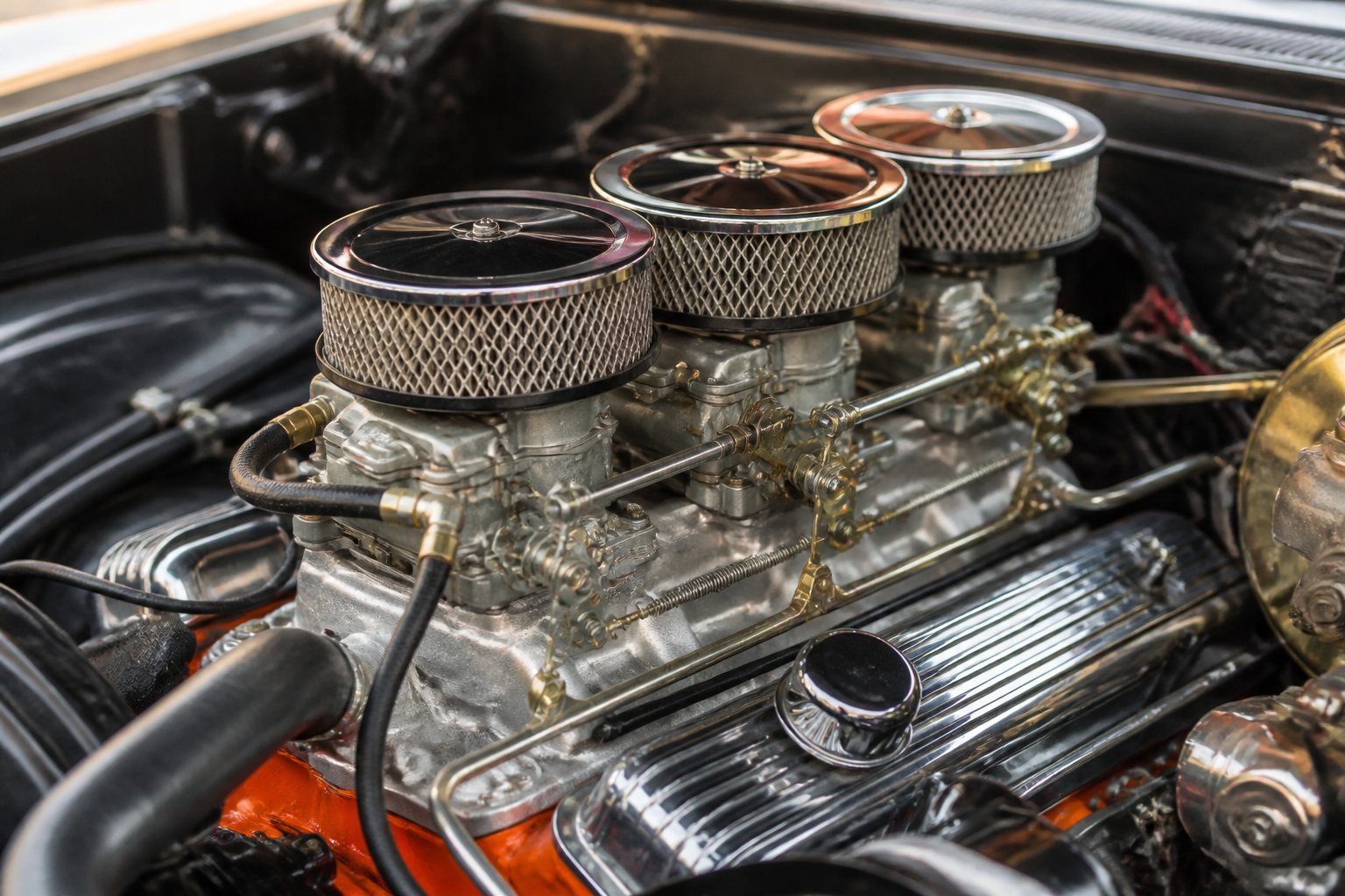 Close-up of a classic 1960s muscle car engine with multiple carburetors and polished chrome parts.