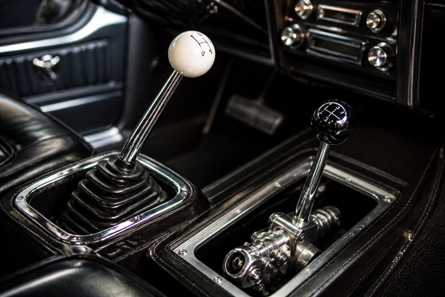 Close-up of manual gear shifters and transmission components inside a vintage 1960s muscle car.
