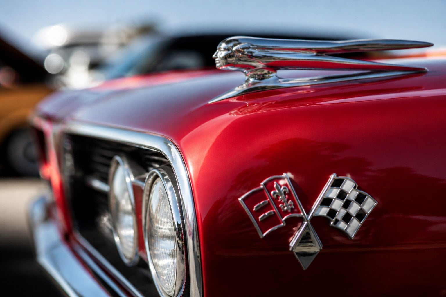 Close-up of a vintage 1960s muscle car hood ornament and rally badges on a polished, colorful car surface.