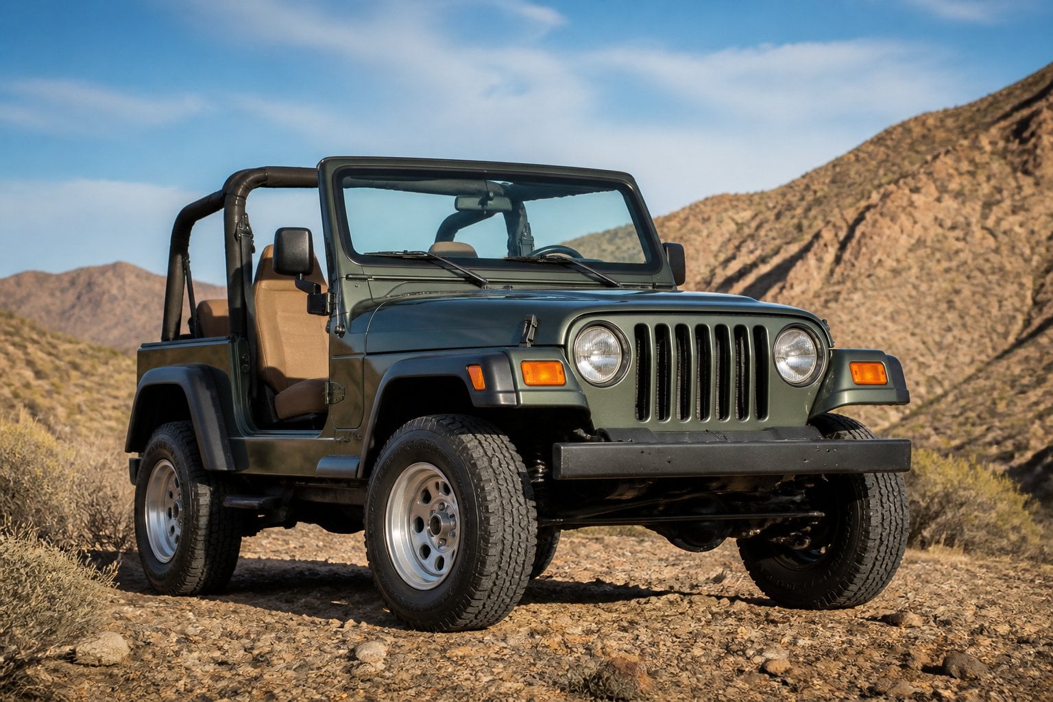 A Jeep Wrangler parked on rocky terrain with hills and desert plants in the background.
