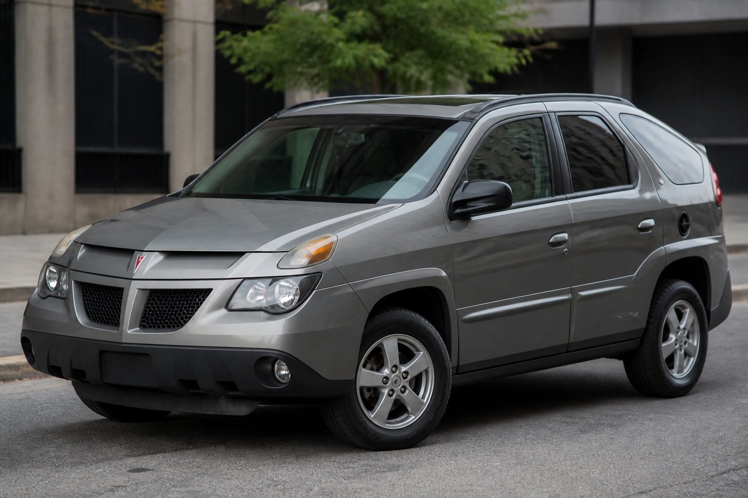 A Pontiac Aztek car parked on a city street, shown from the front side angle.