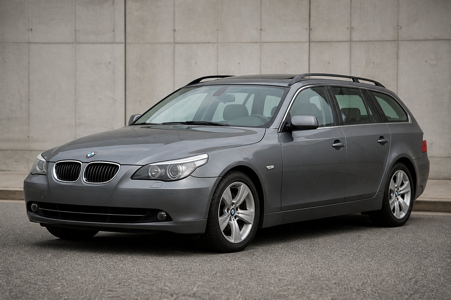 A gray BMW 5 Series E61 Touring station wagon parked on a quiet roadside.