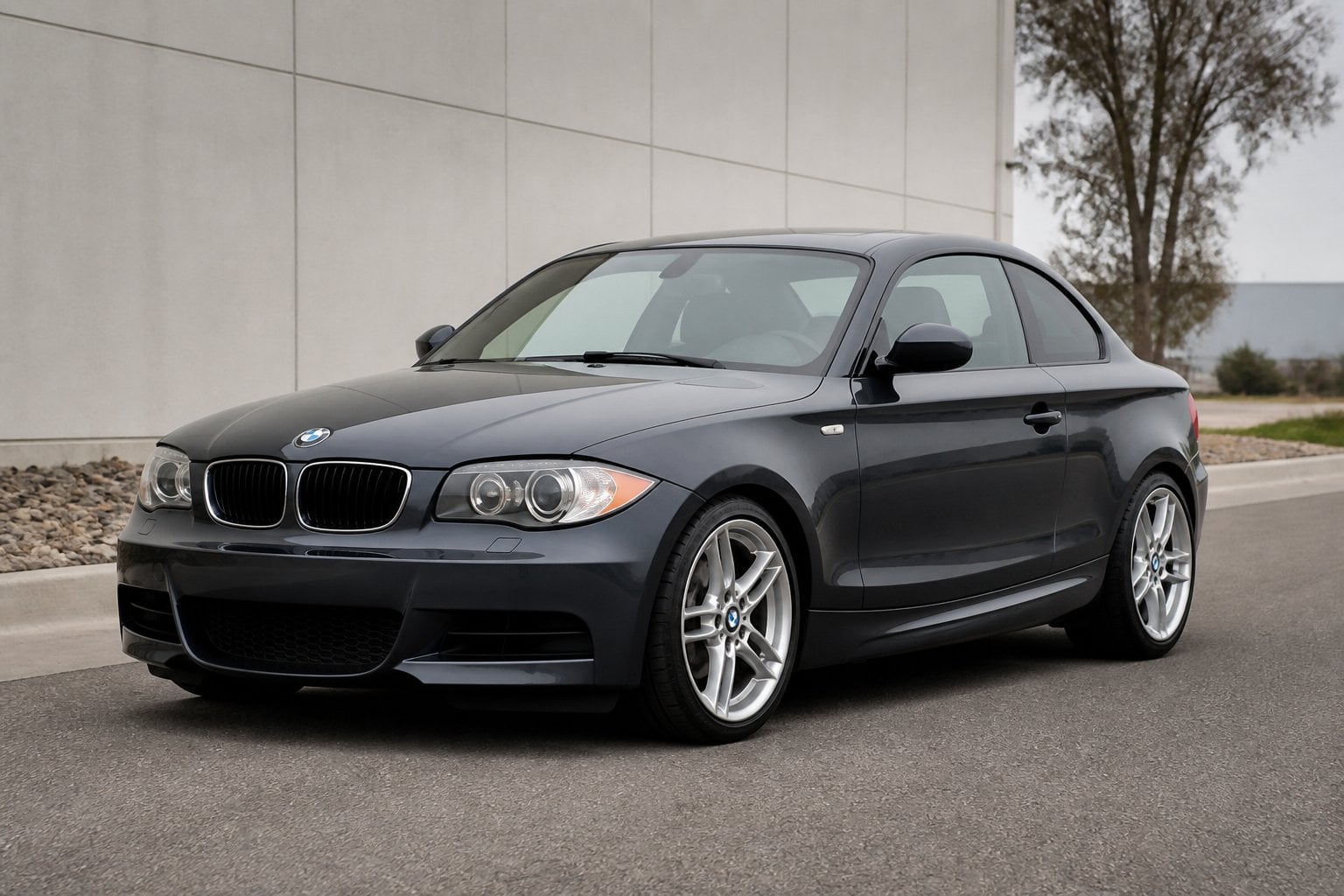 A dark blue BMW 1 Series 135i coupe parked on a quiet paved road.