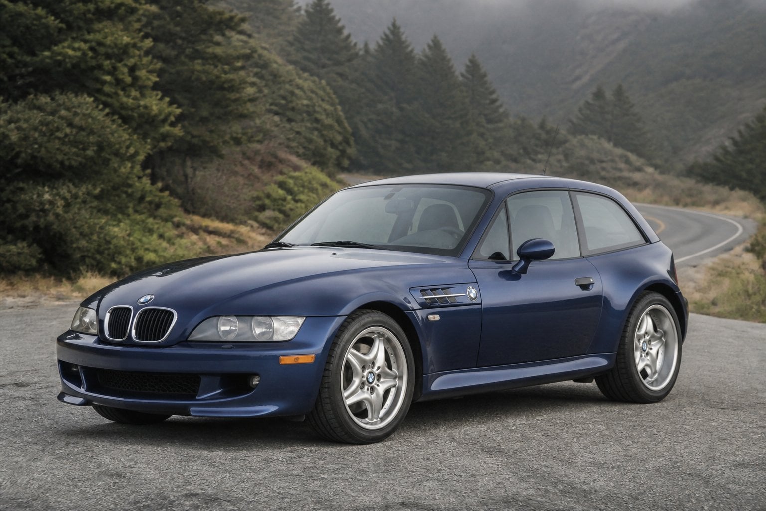 A blue BMW Z3 coupe parked on a winding mountain road.