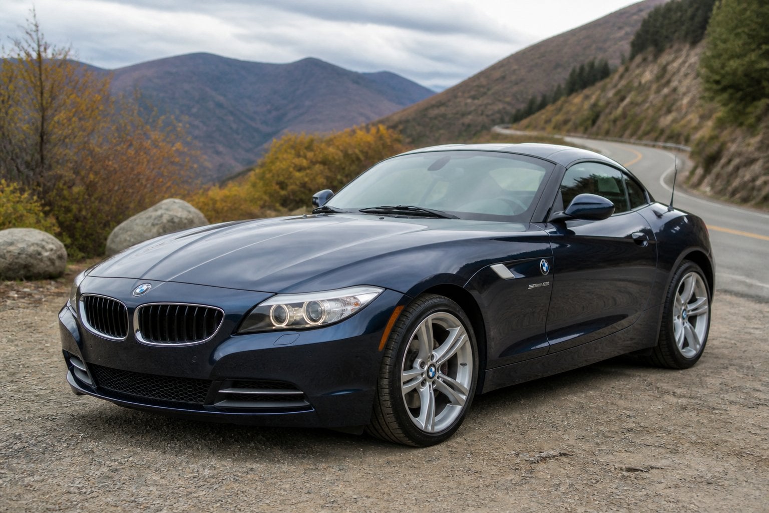 A gray BMW Z4 convertible parked on a winding mountain road.