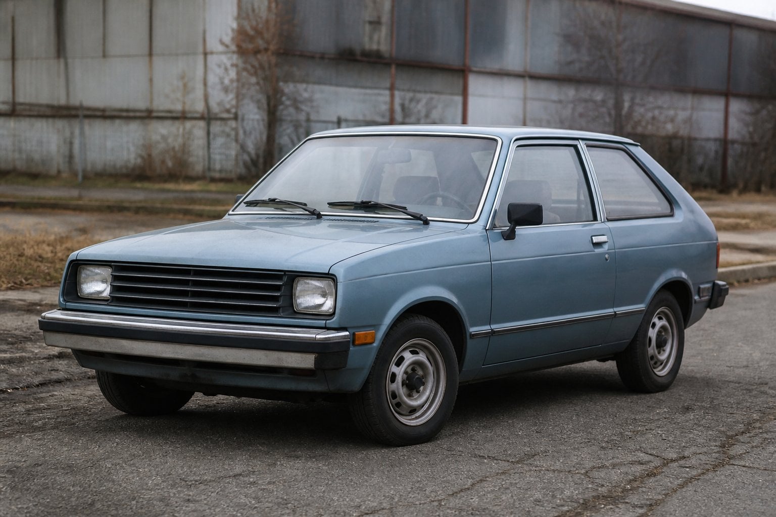 A vintage Chevrolet Chevette parked beside a weathered industrial roadside.
