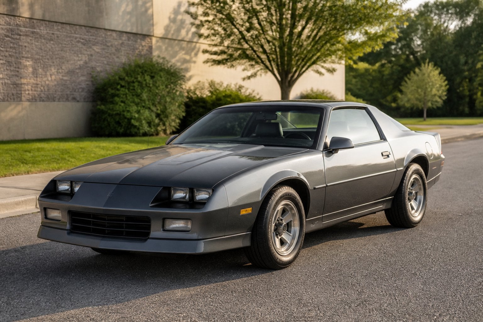 A gray 1982 Chevrolet Camaro parked on a paved roadside.