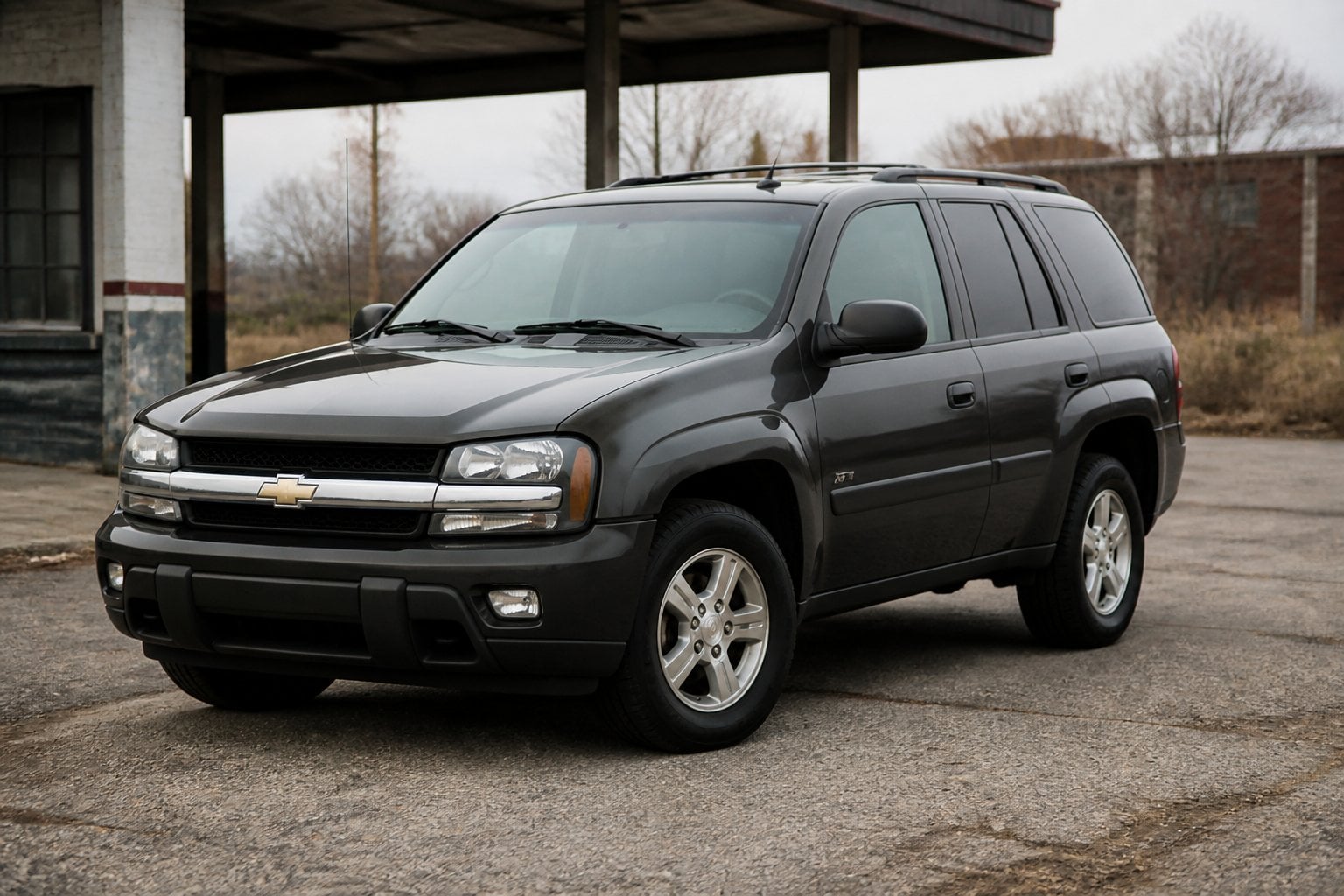 A first-generation Chevrolet Trailblazer SUV parked beside a worn roadside service area.