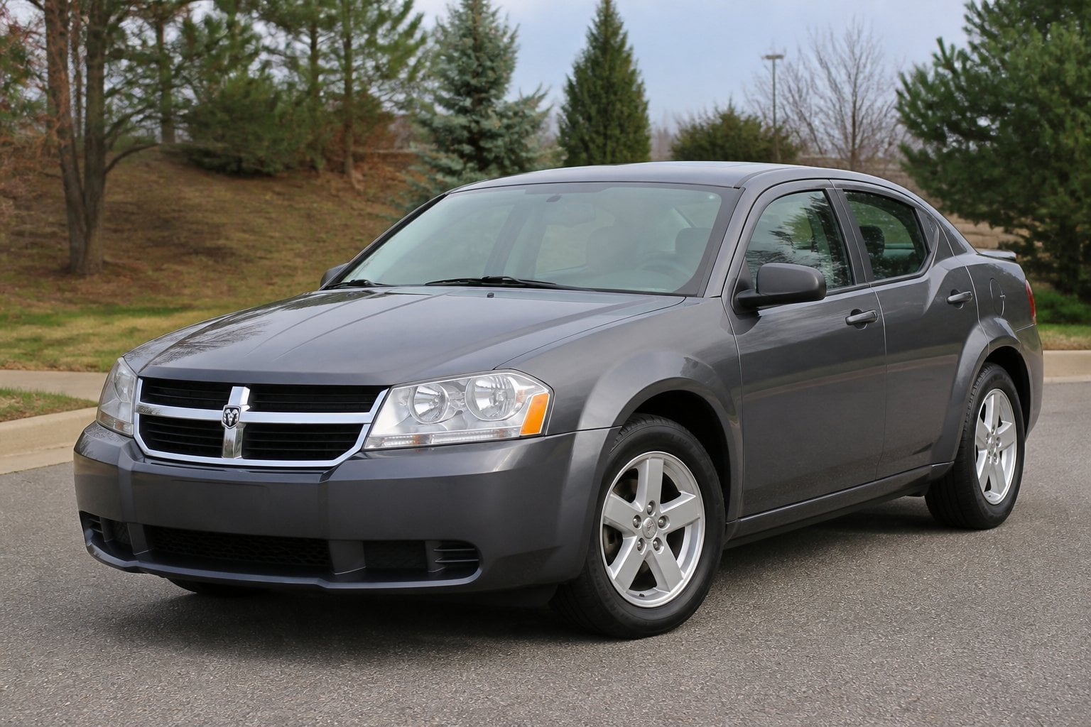 A gray Dodge Avenger sedan parked on a quiet roadside in daylight.