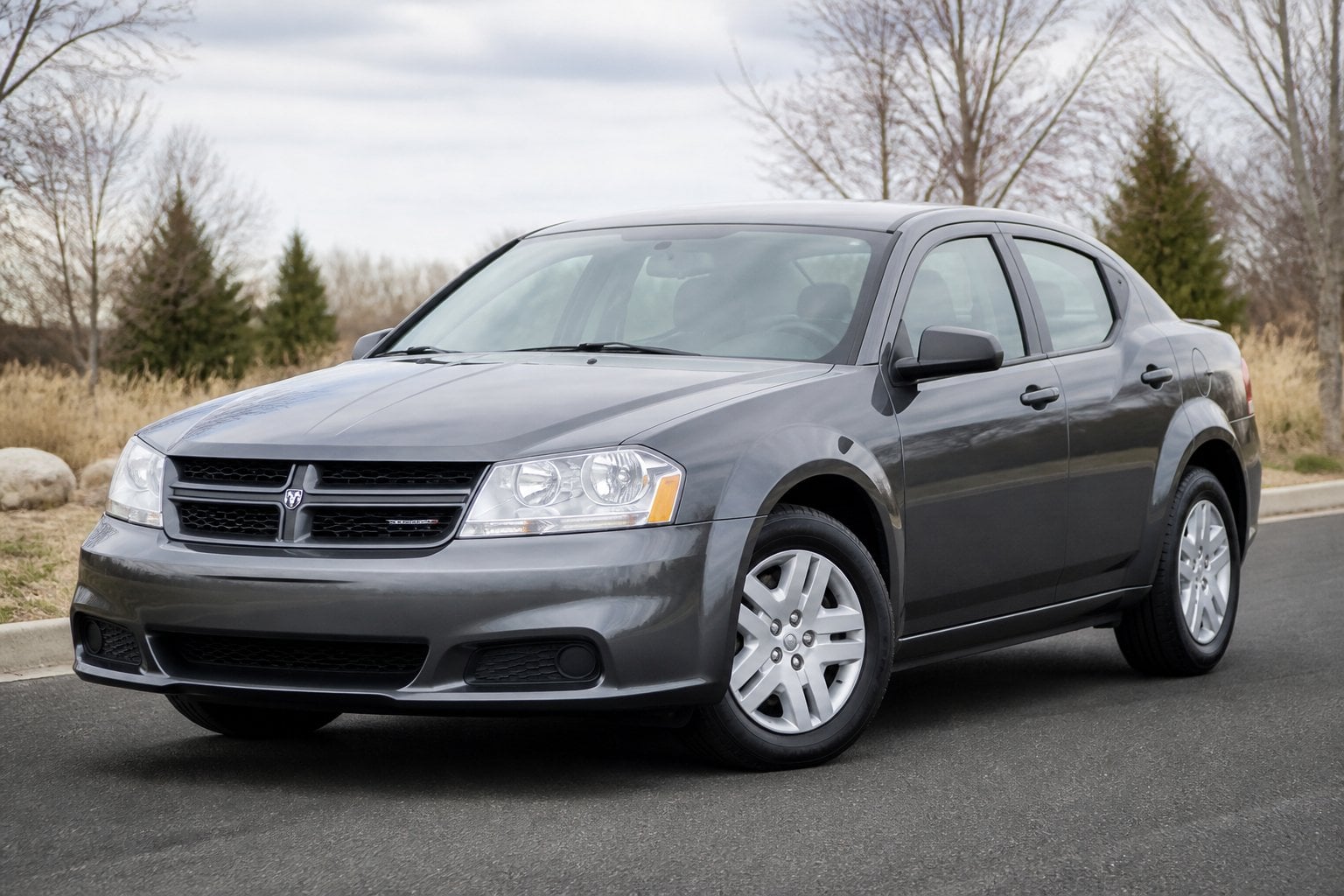 A silver Dodge Avenger sedan parked on a quiet roadside in daylight.