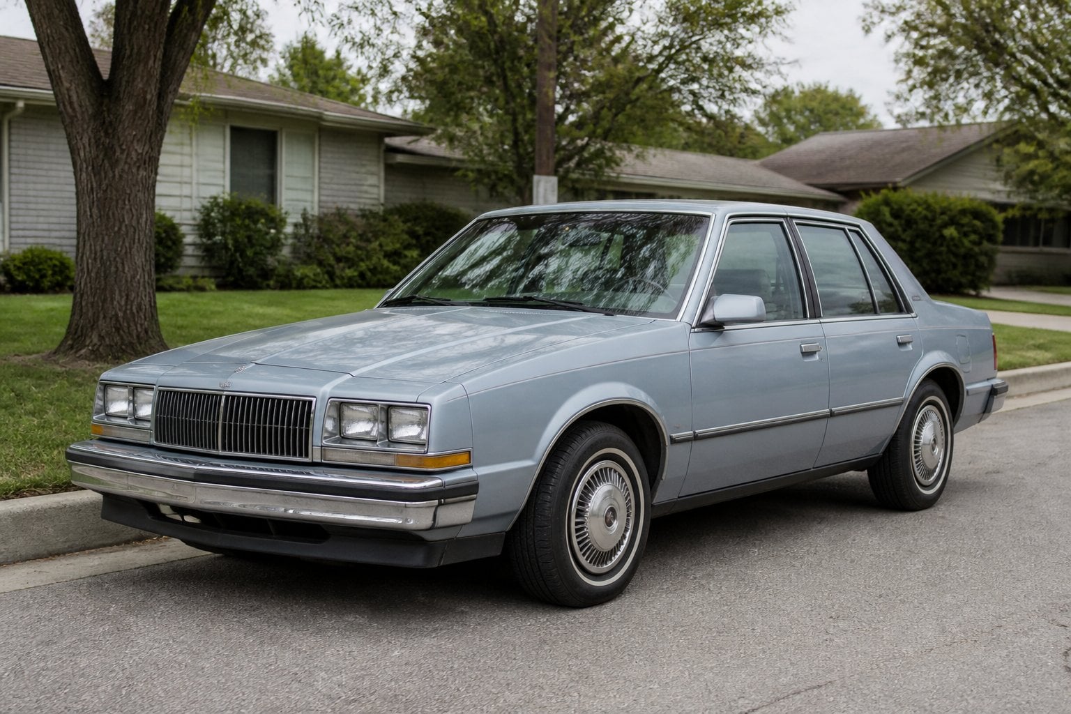 A vintage Cadillac Cimarron parked on a quiet suburban street.