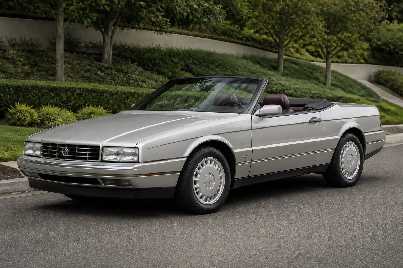 A vintage Cadillac Allanté convertible parked on a quiet landscaped road.
