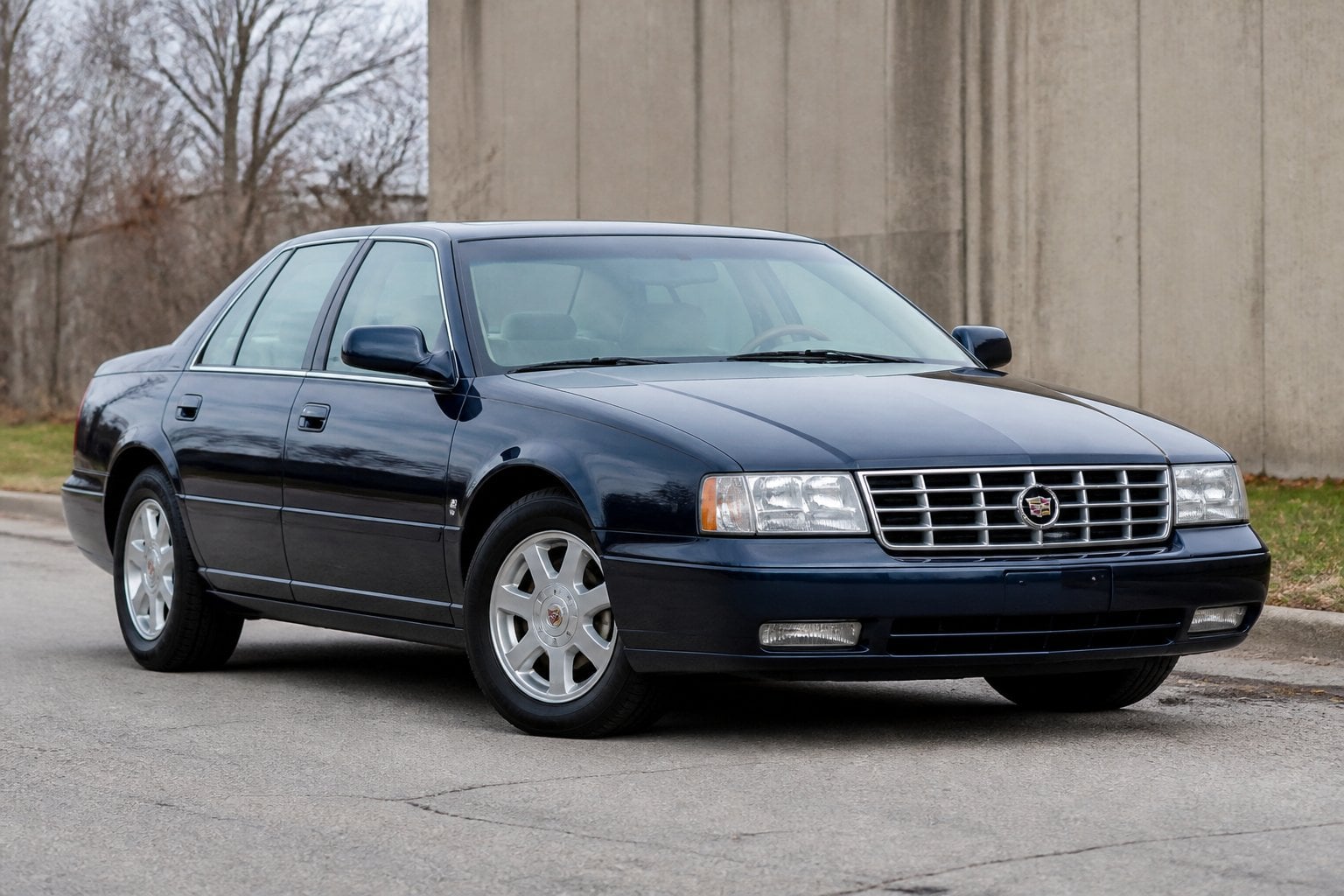 A Cadillac Seville STS sedan parked on a quiet roadside.