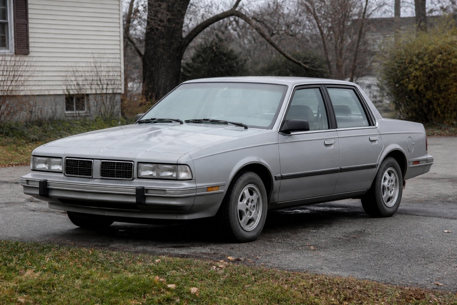 A boxy older Pontiac 6000 sedan parked in a modest outdoor setting.