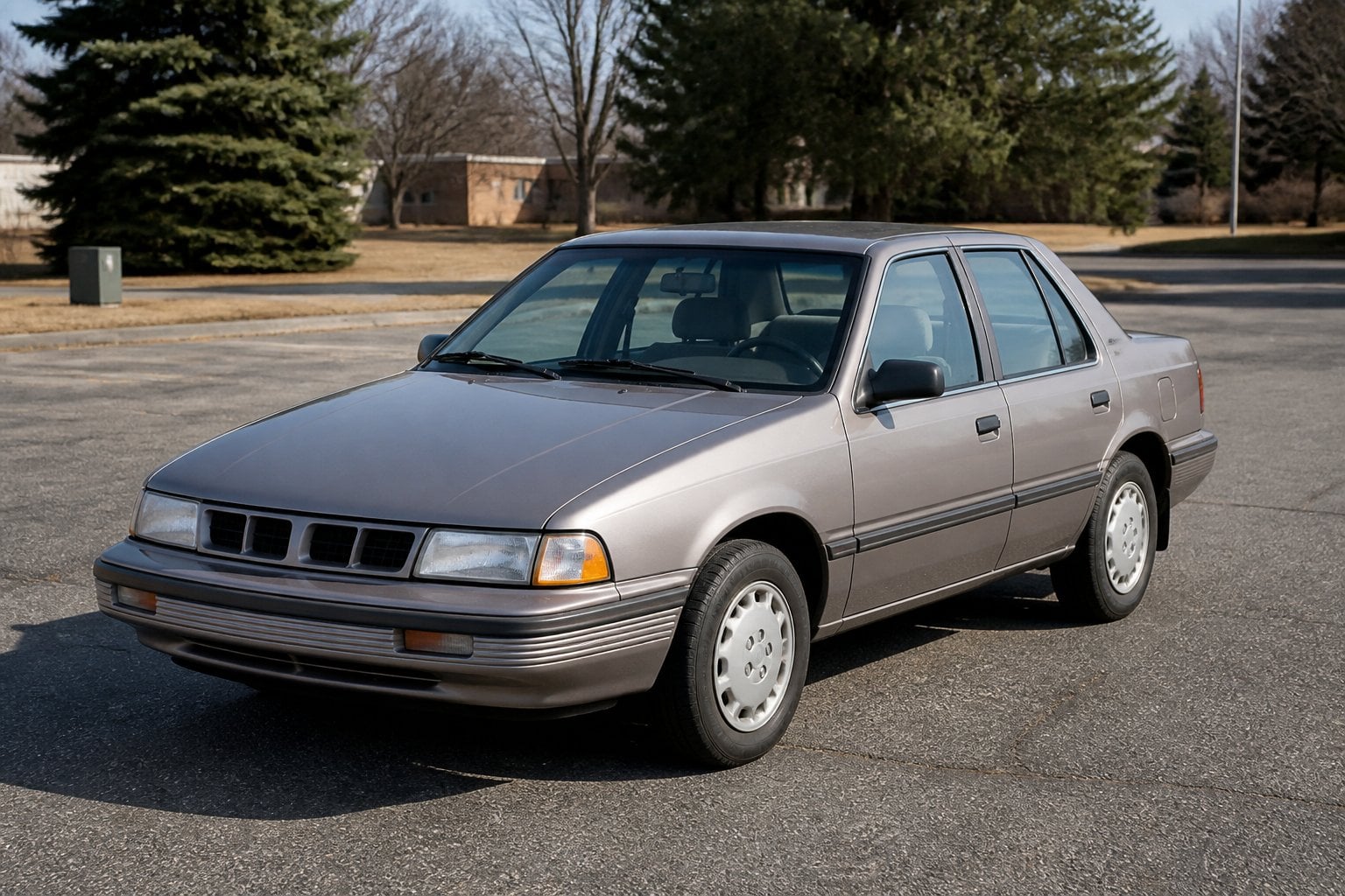 A 1988–1993 Pontiac LeMans sedan parked beside a quiet roadside in daylight.