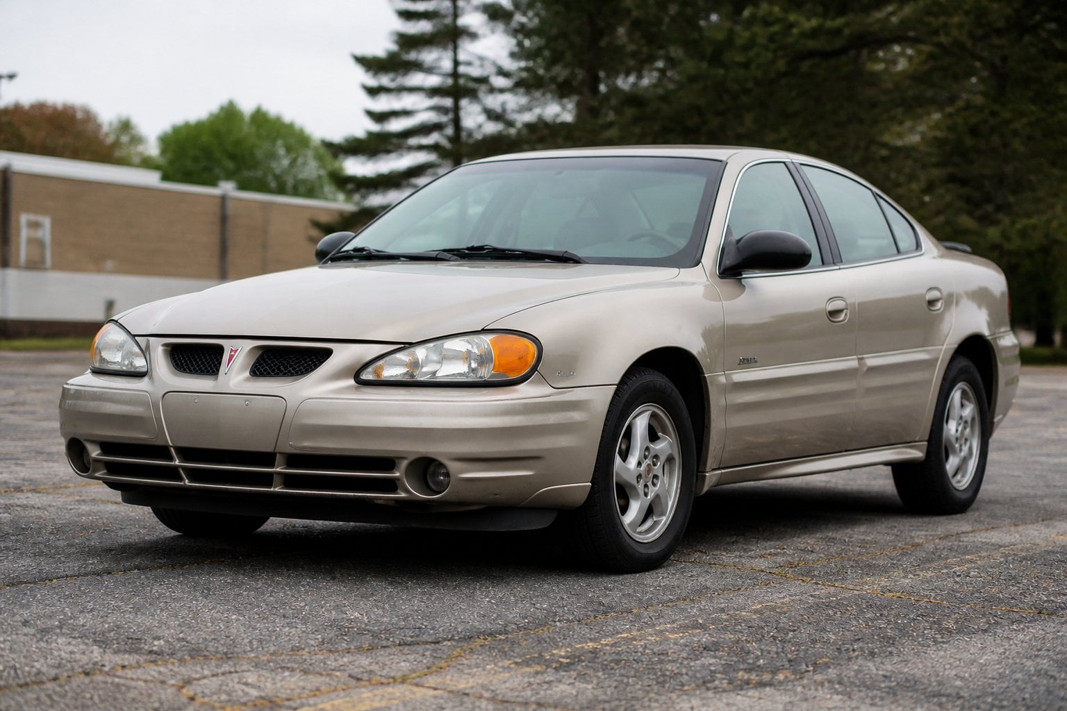 A weathered Pontiac Grand Am sedan parked in a suburban lot.