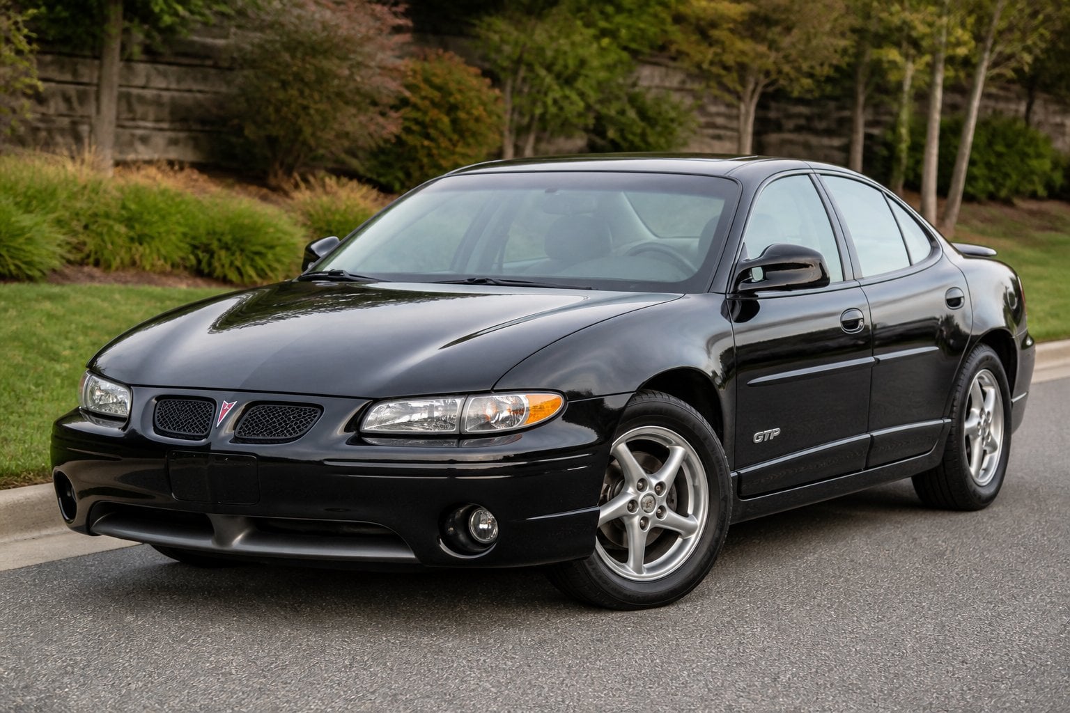 A Pontiac Grand Prix GTP parked on a quiet paved street in daylight.