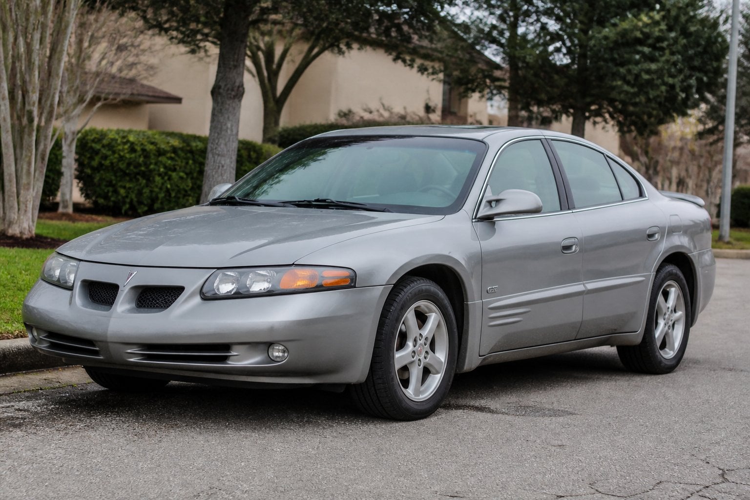 A Pontiac Bonneville sedan from the early 2000s parked on a quiet roadside.