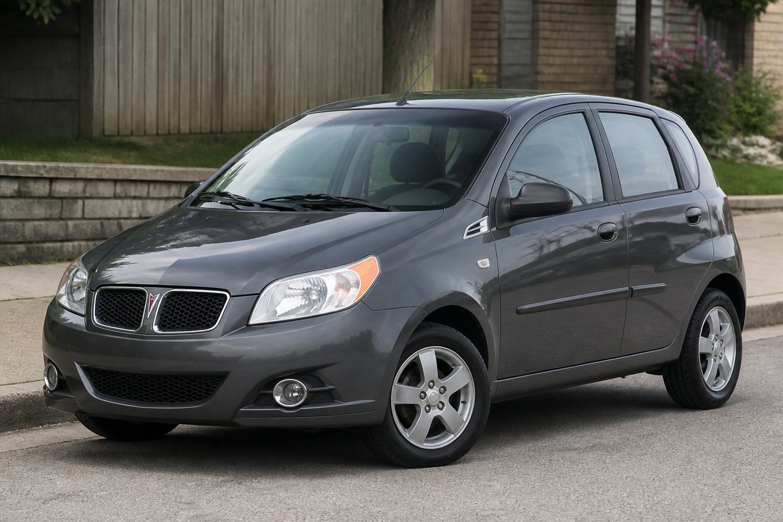 A compact Pontiac G3 hatchback parked on a suburban roadside.