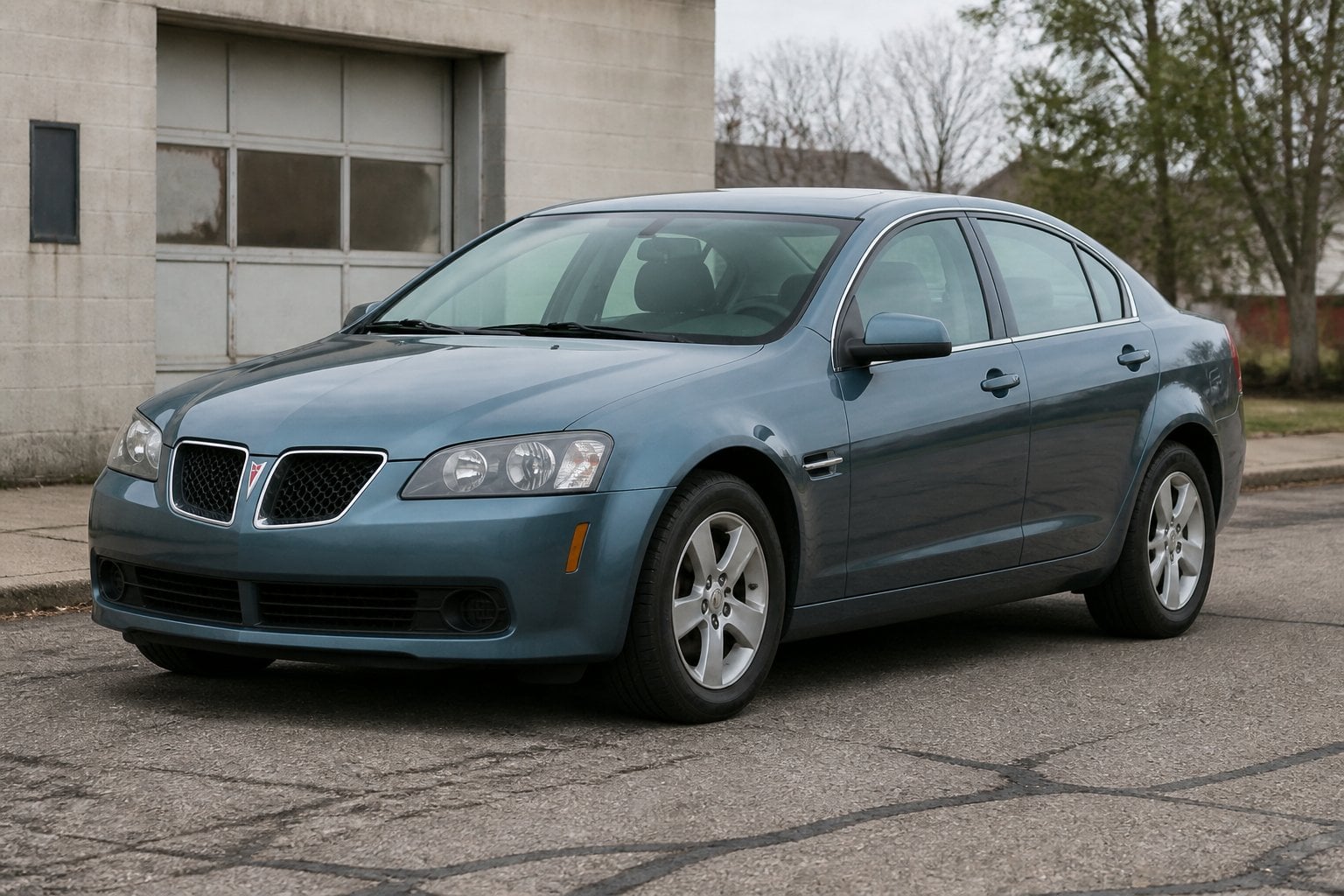A Pontiac G8 sedan parked beside an aging roadside automotive facility.