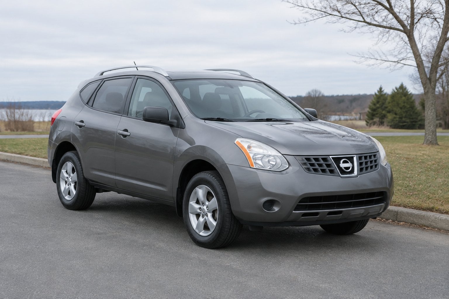 A 2009 Nissan Rogue compact SUV parked beside a suburban roadside.