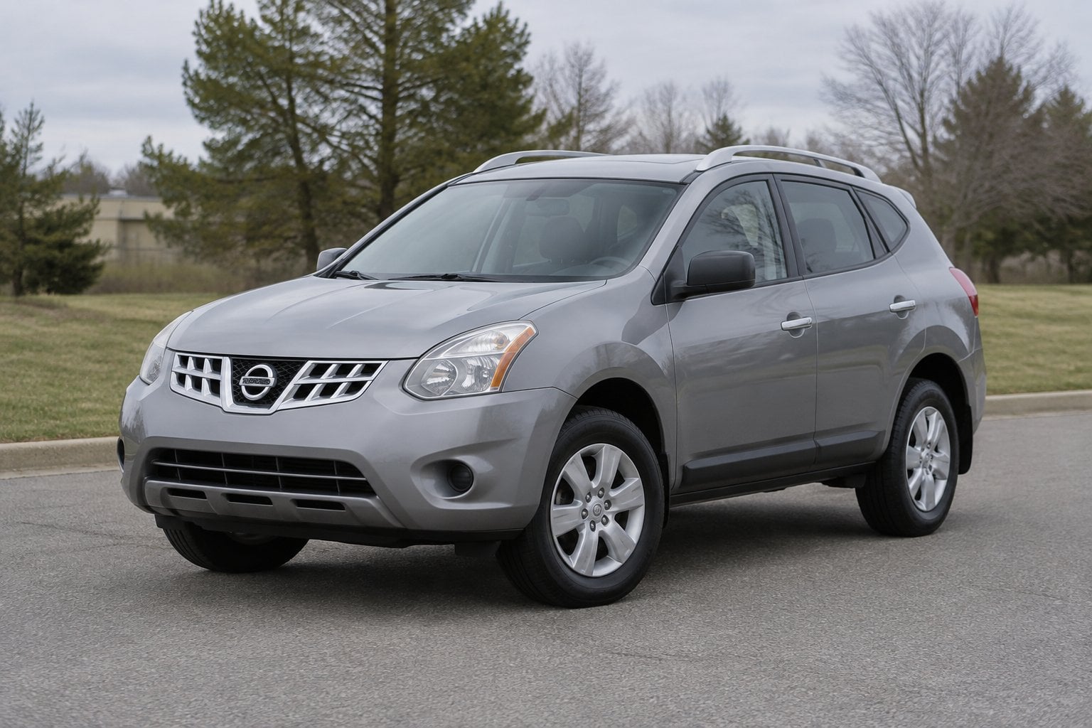 A silver 2011 Nissan Rogue parked on a suburban roadside.