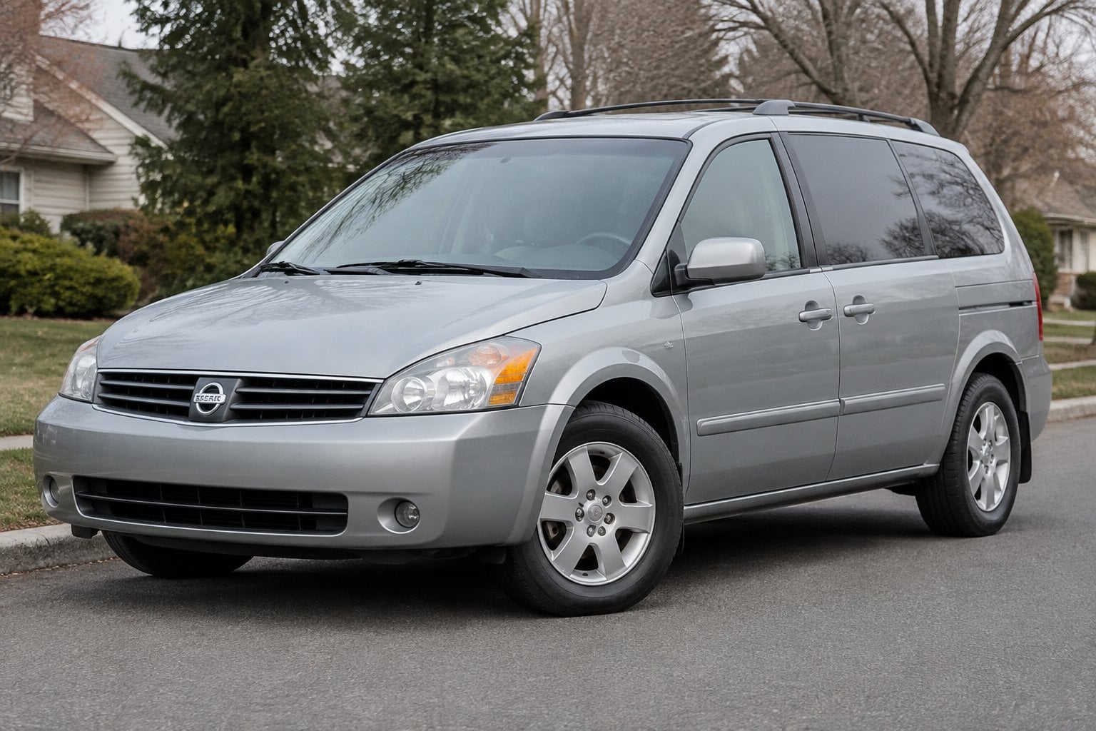 A 2004 Nissan Quest minivan parked on a quiet suburban street.