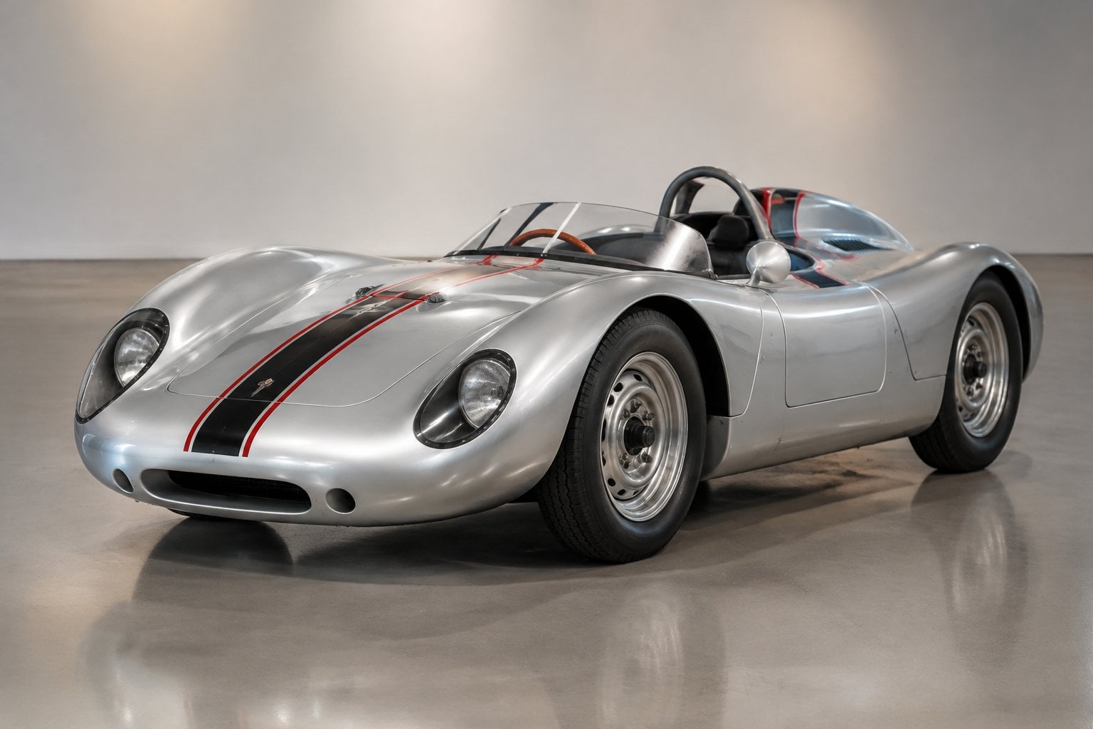 A silver vintage Porsche racing car displayed indoors.