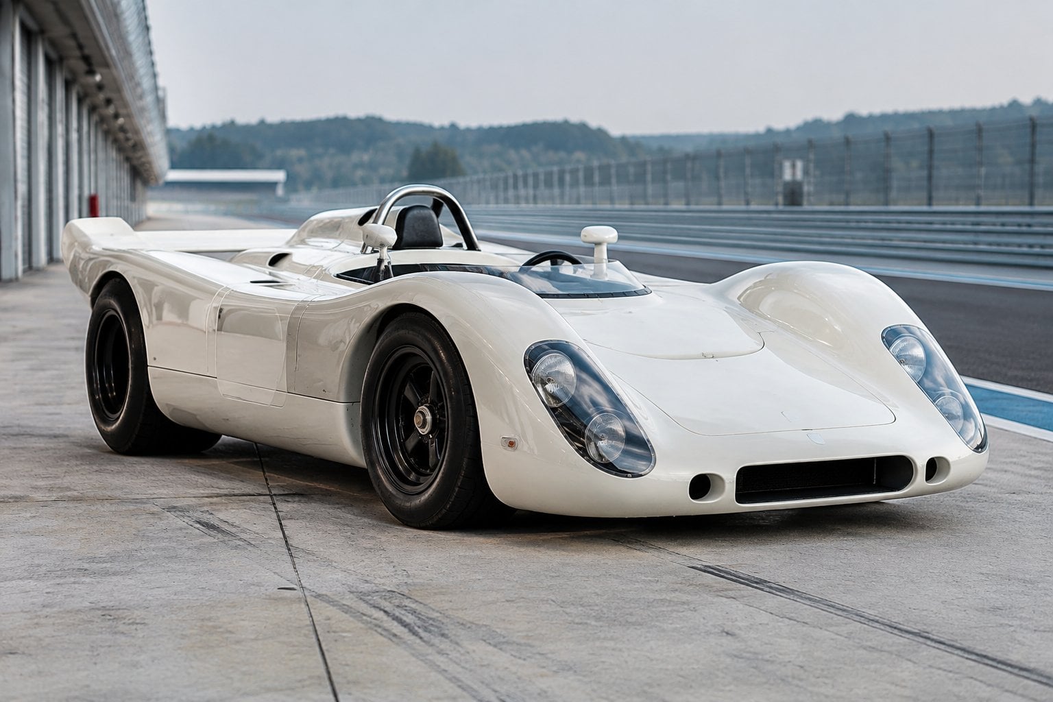 A vintage Porsche racing car parked in a quiet pit lane.