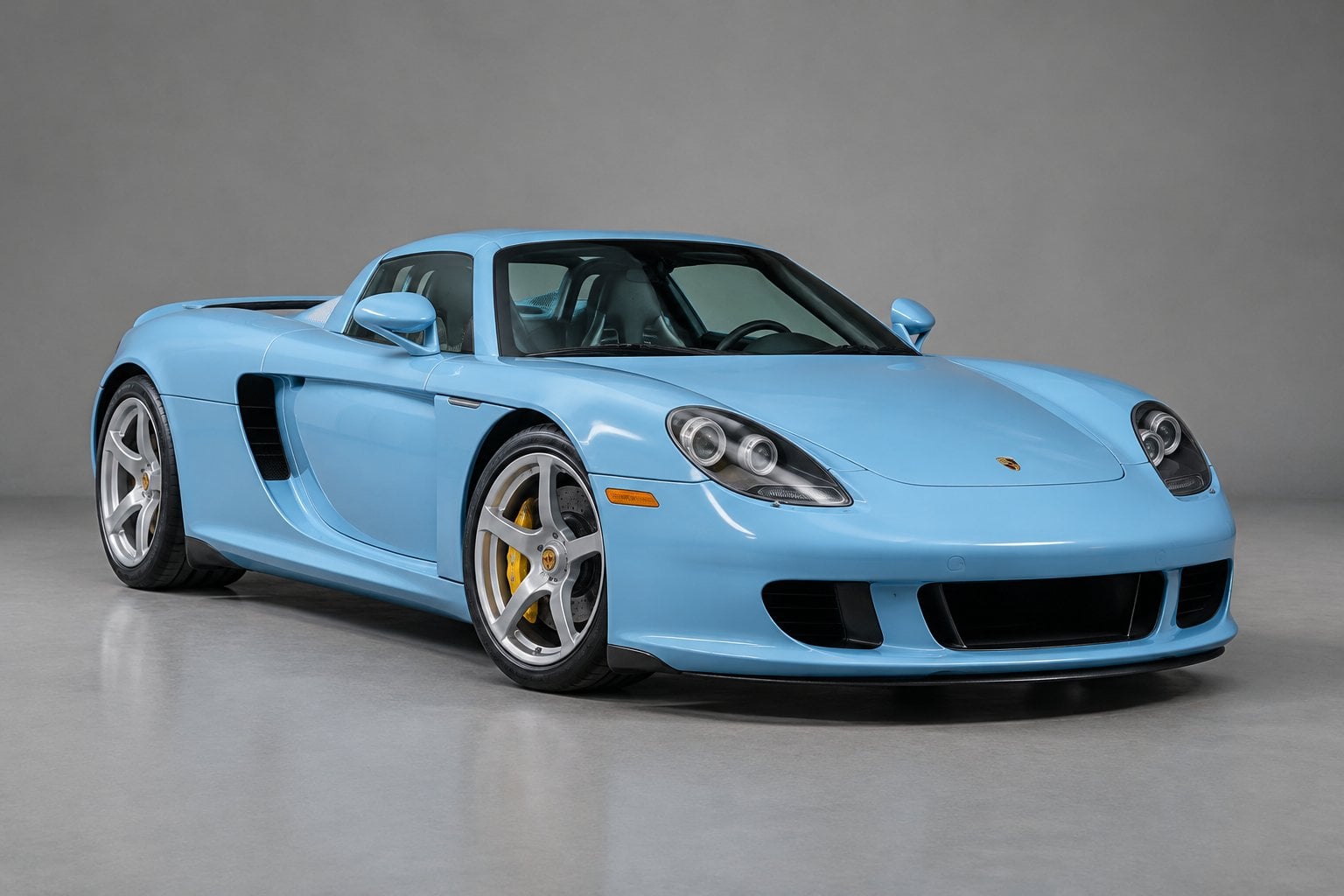 A blue Porsche Carrera GT parked in a studio.