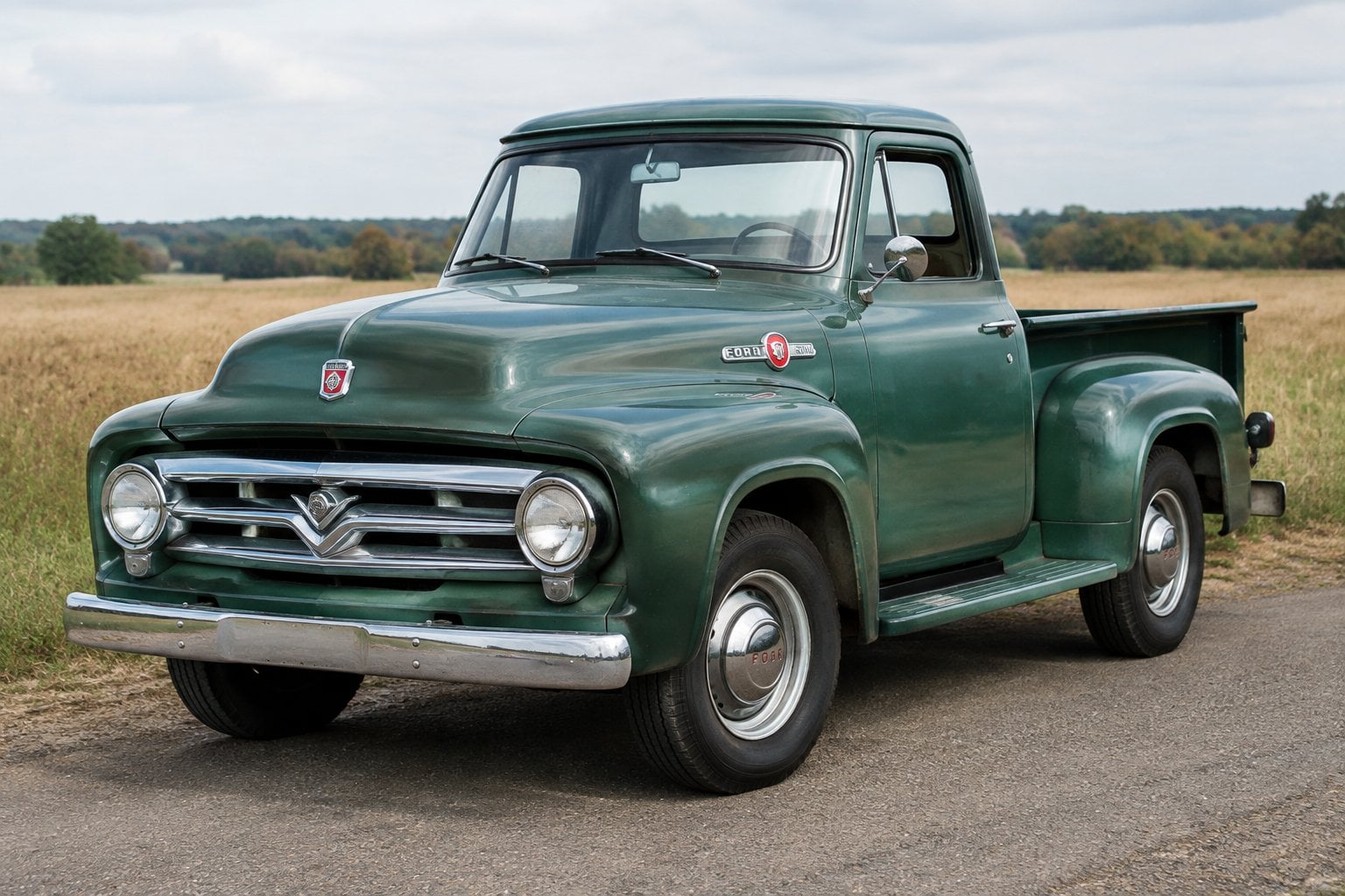 A vintage pickup truck parked on a country road beside an open field.