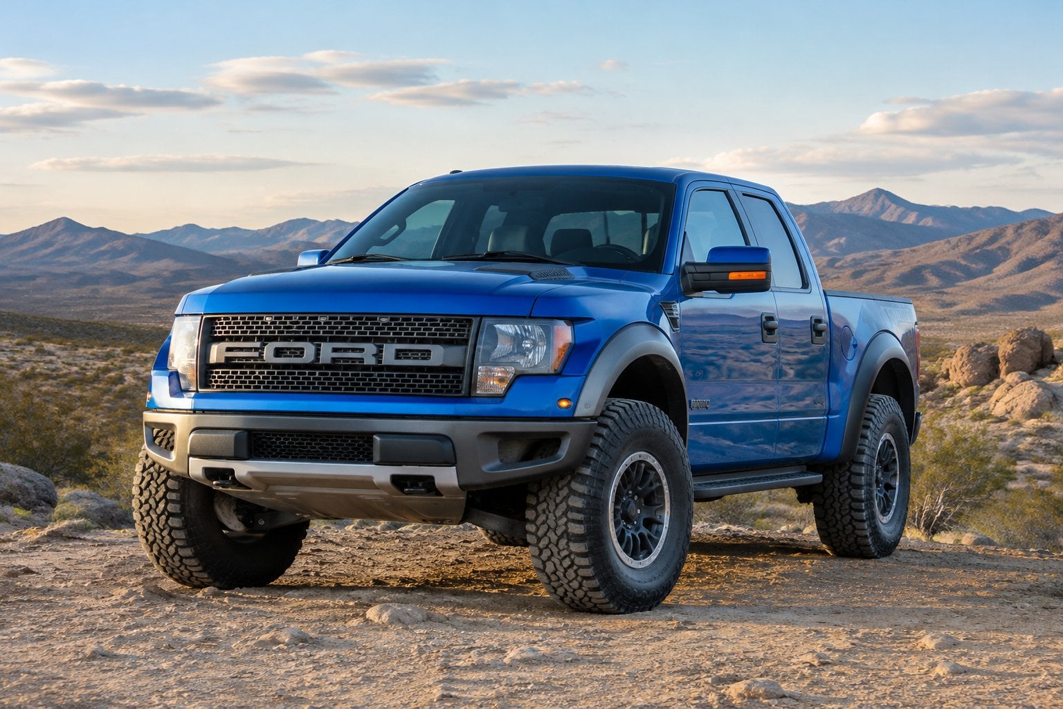A red Ford F-150 Raptor parked on a rocky desert trail.