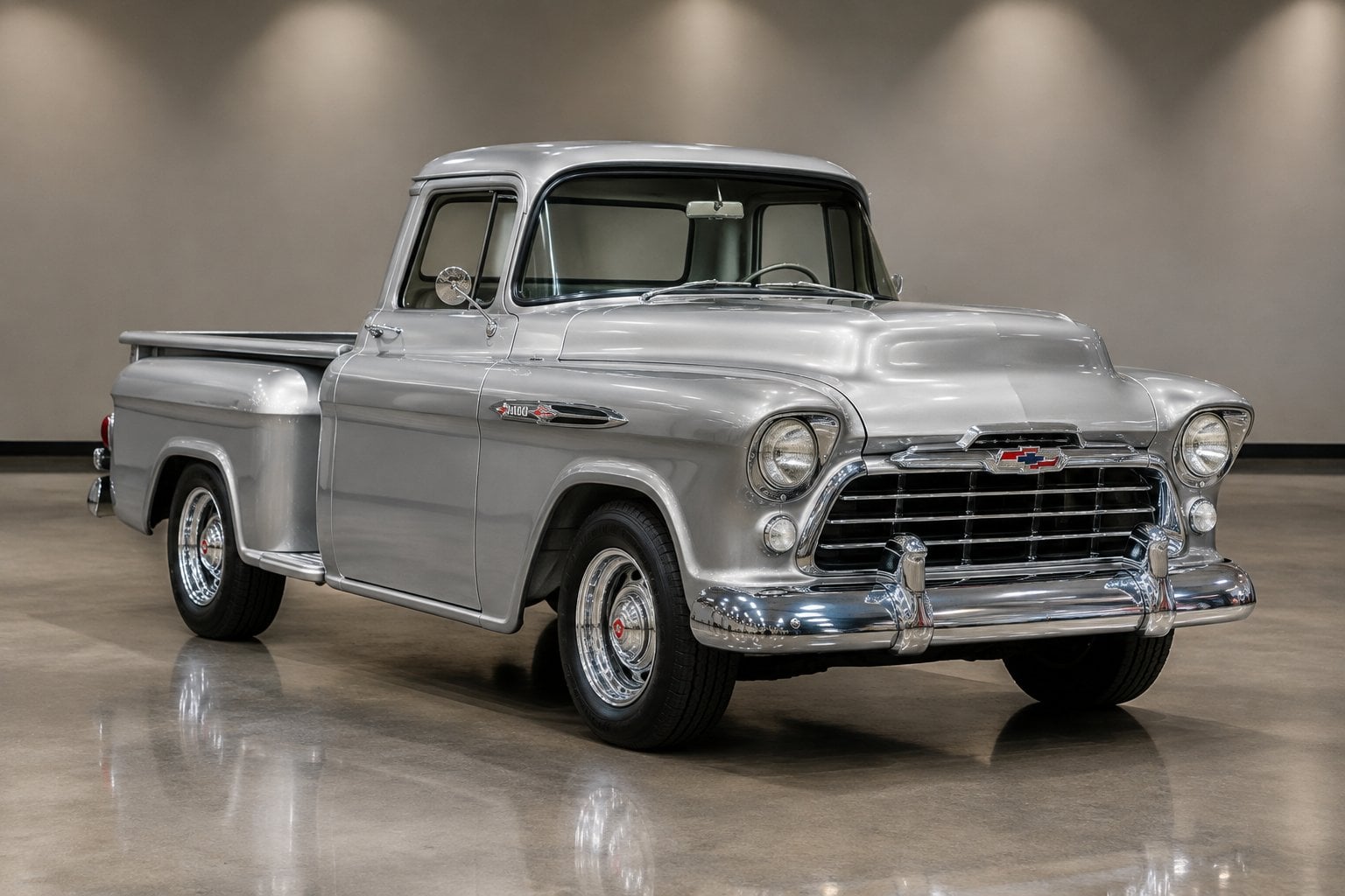 A silver 1957 Chevrolet pickup truck displayed in an auction hall.